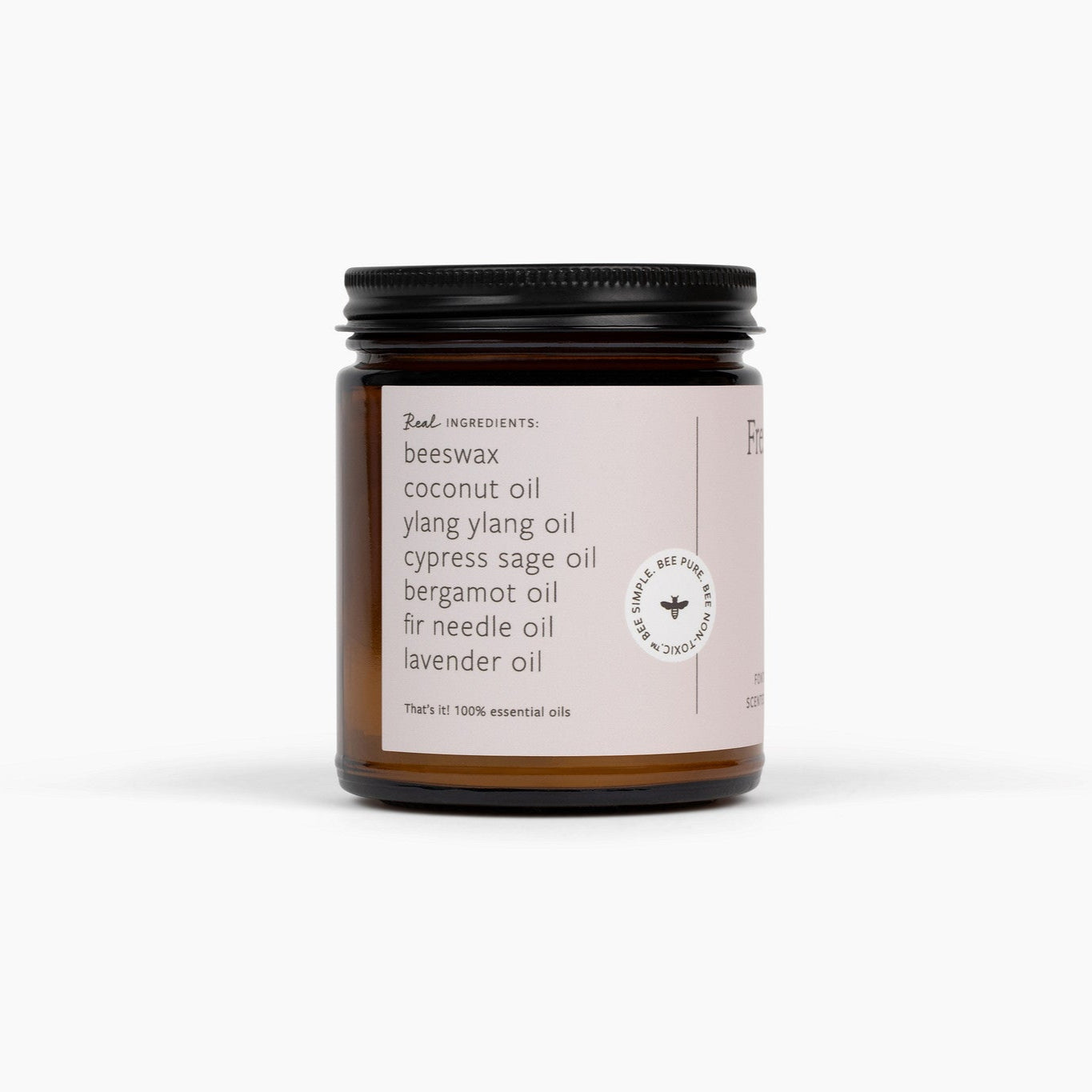 Side view of an amber glass jar candle with a black lid and a soft pink label. The candle is in front of a white background. 