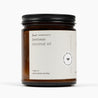 Side shot of an amber glass jar candle with a white label and the ingredients: beeswax and coconut oil. 