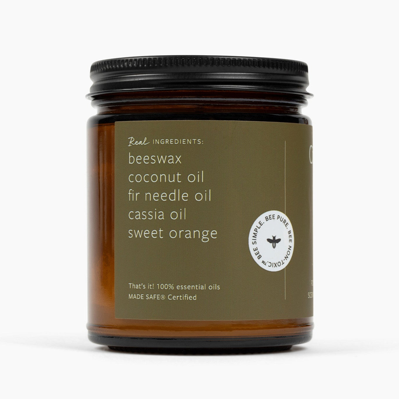 Side angle of amber glass jar candle with a military green colored label and an ingredient list with: beeswax, coconut oil, fir needle oil, cassia oil, and sweet orange.