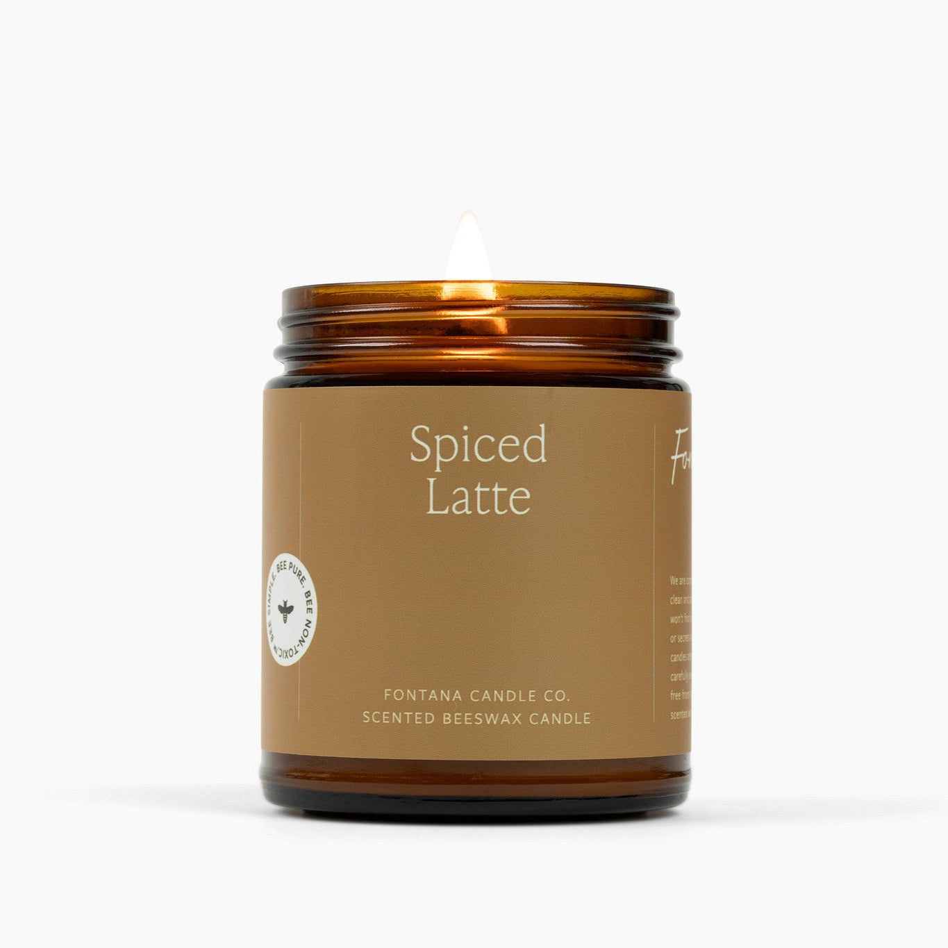Lit amber glass jar candle with a brown label and Spiced Latte scent.