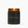 Lit amber glass jar candle with a very dark green label that says: Season's Greetings: the best time of year."