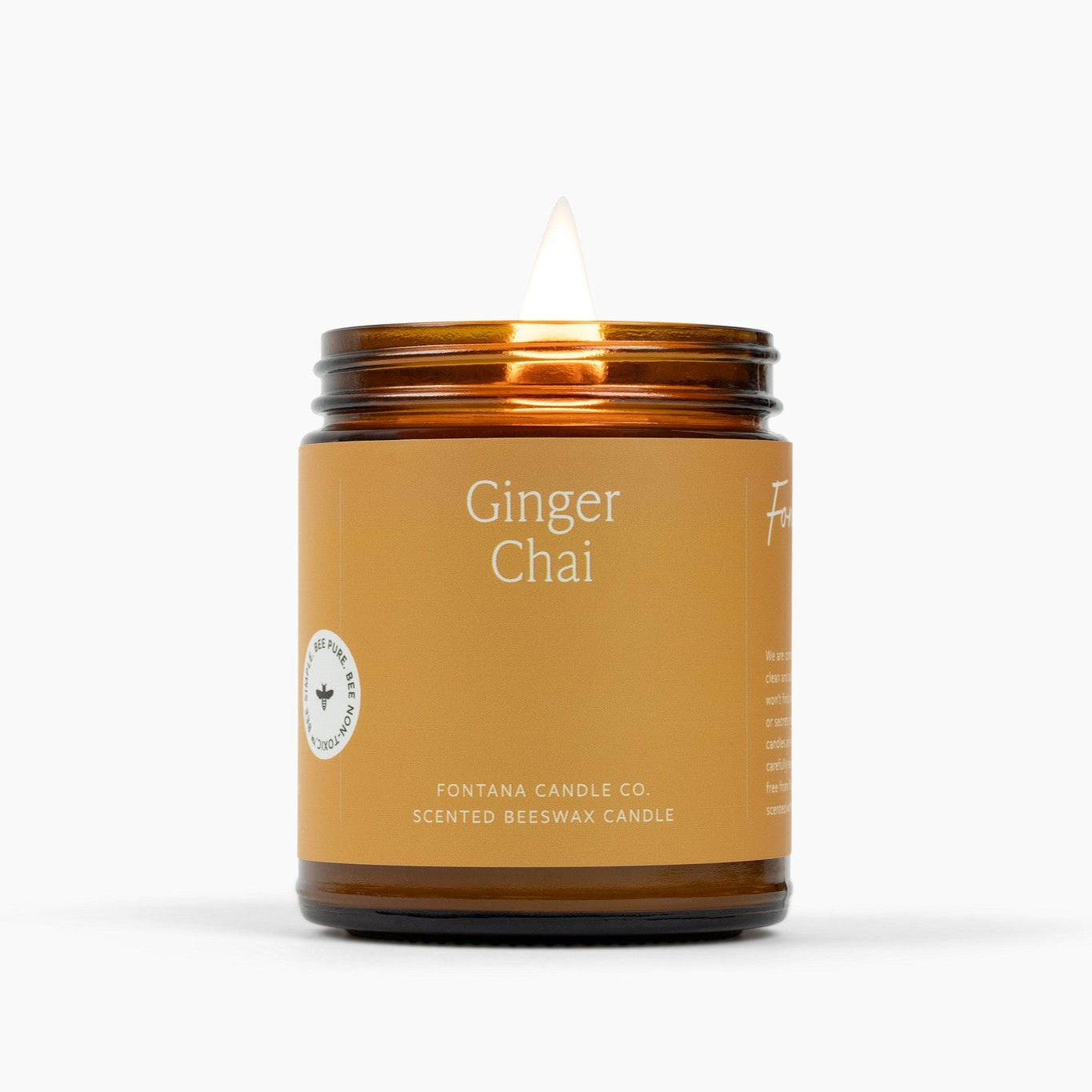 Lit amber glass jar candle with a warm golden color label and the scent name Ginger Chai.