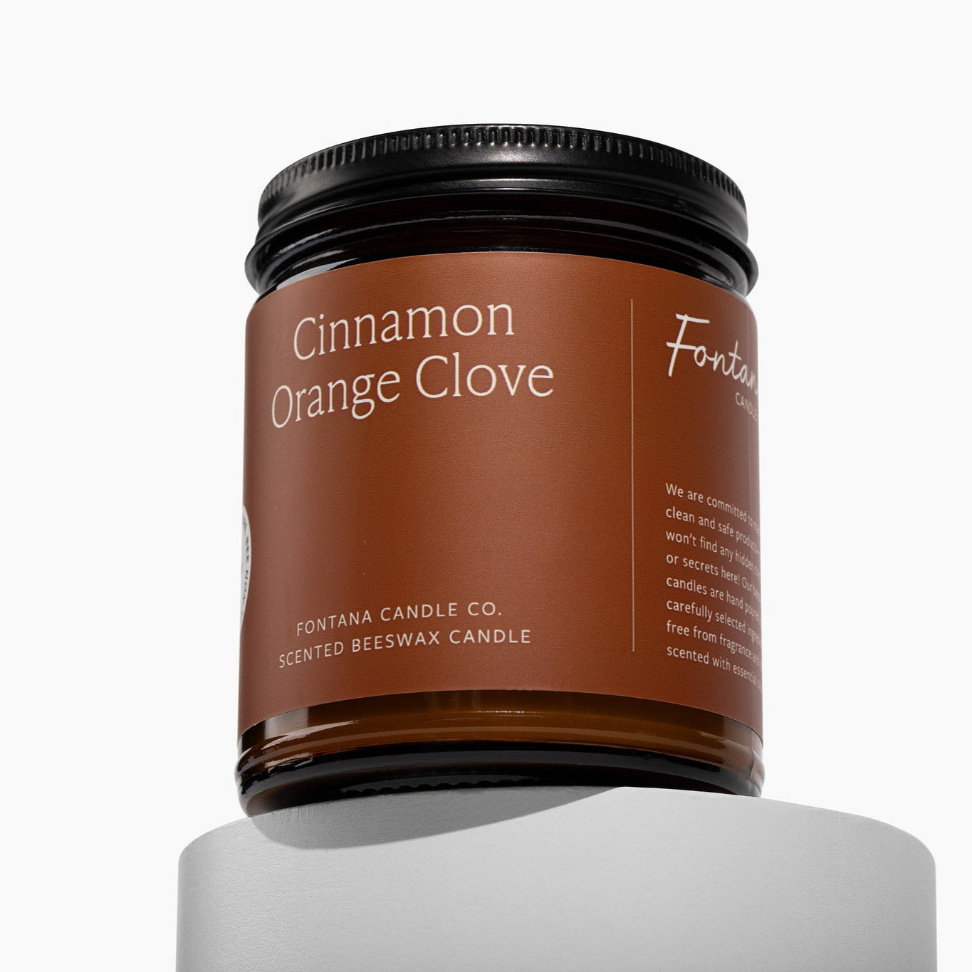 Amber glass jar Candle with 'Cinnamon Orange Clove' on a deep orange label on a white background