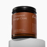 Amber glass jar Candle with 'Cinnamon Orange Clove' on a deep orange label on a white background
