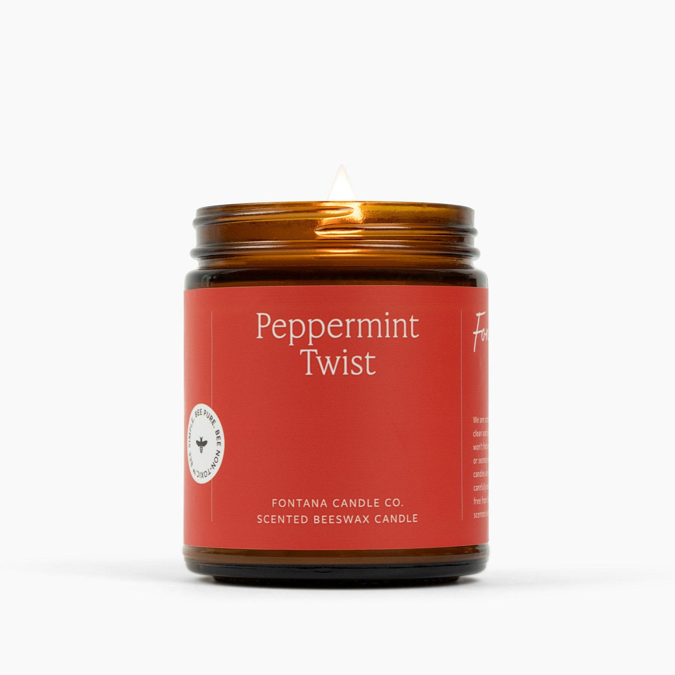 Lit amber glass jar candle with a red label and Peppermint Twist scent.