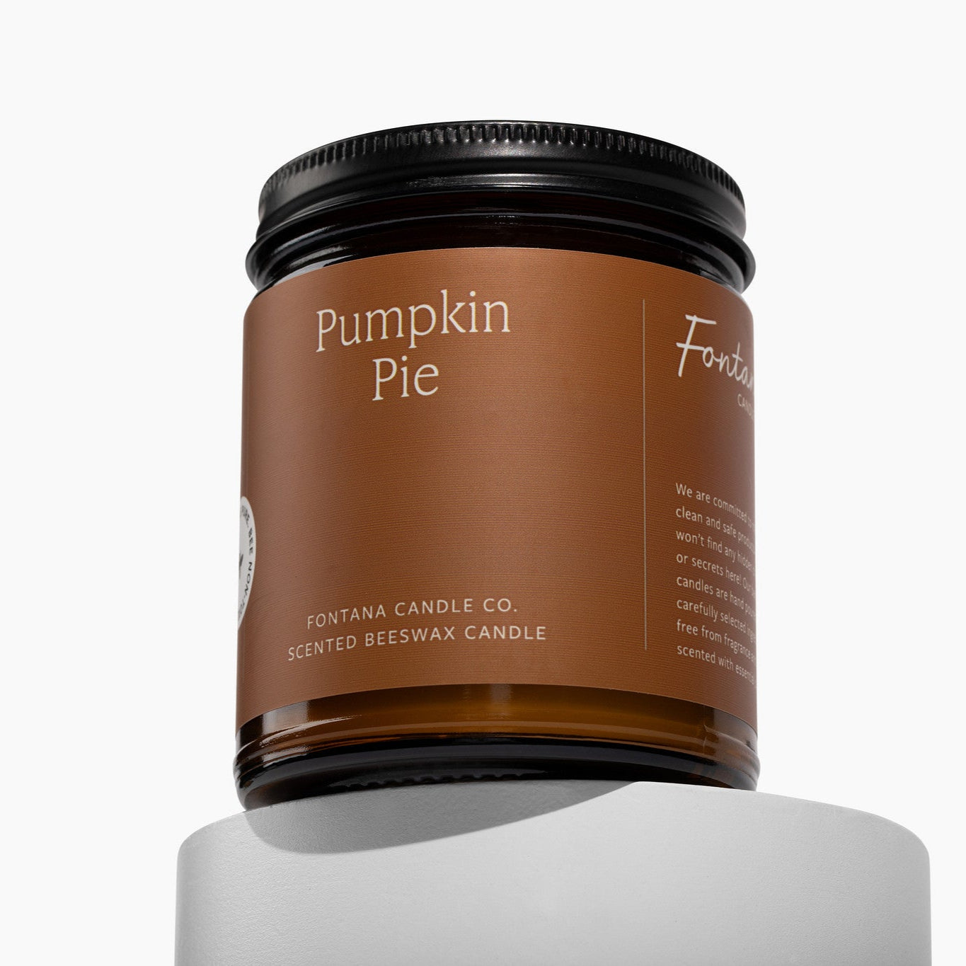 Amber glass jar candle with Pumpkin Pie on a deep orange label, in front of a white background.