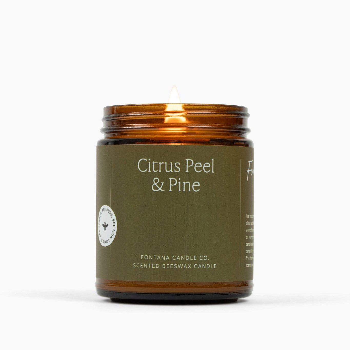 Lit amber glass jar candle with a military green label and Citrus Peel & Pine scent.