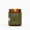 Lit amber glass jar candle with a military green label and Citrus Peel & Pine scent.