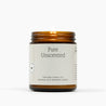 Lit amber glass jar candle with a white label for Pure Unscented. 