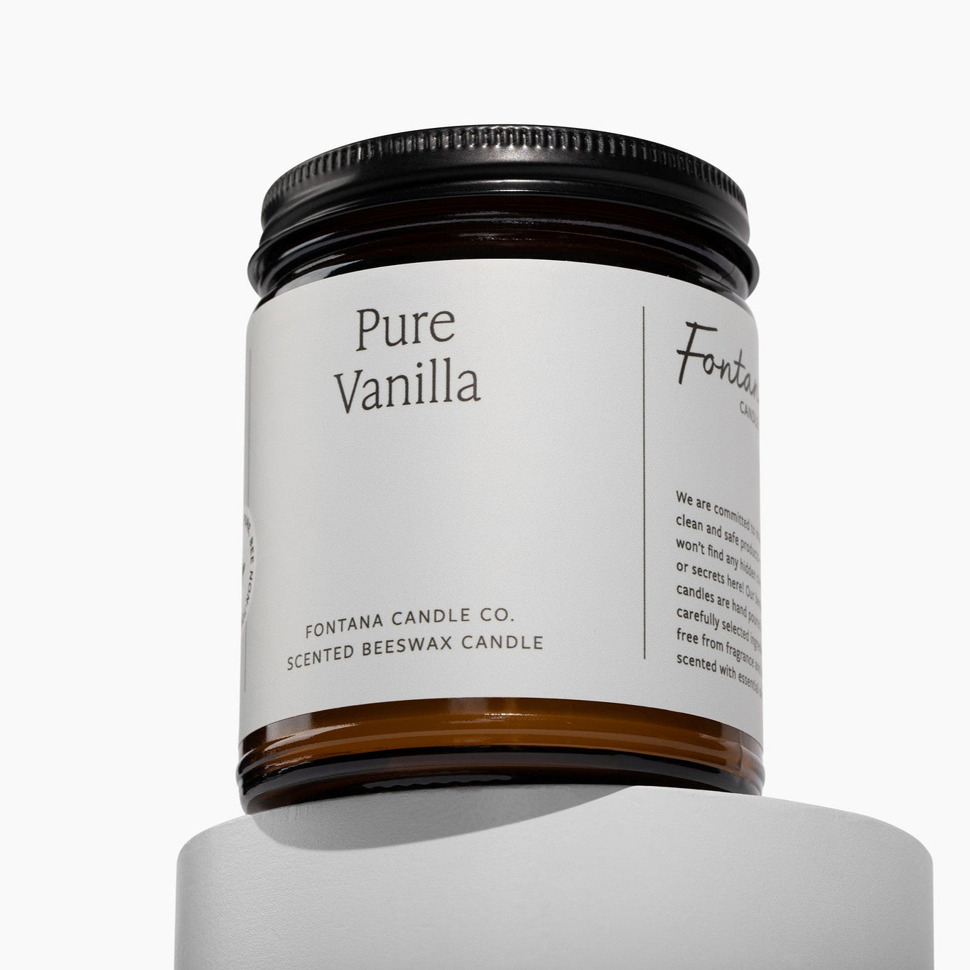 Amber glass jar candle with a white label and Pure Vanilla on front of a white background.