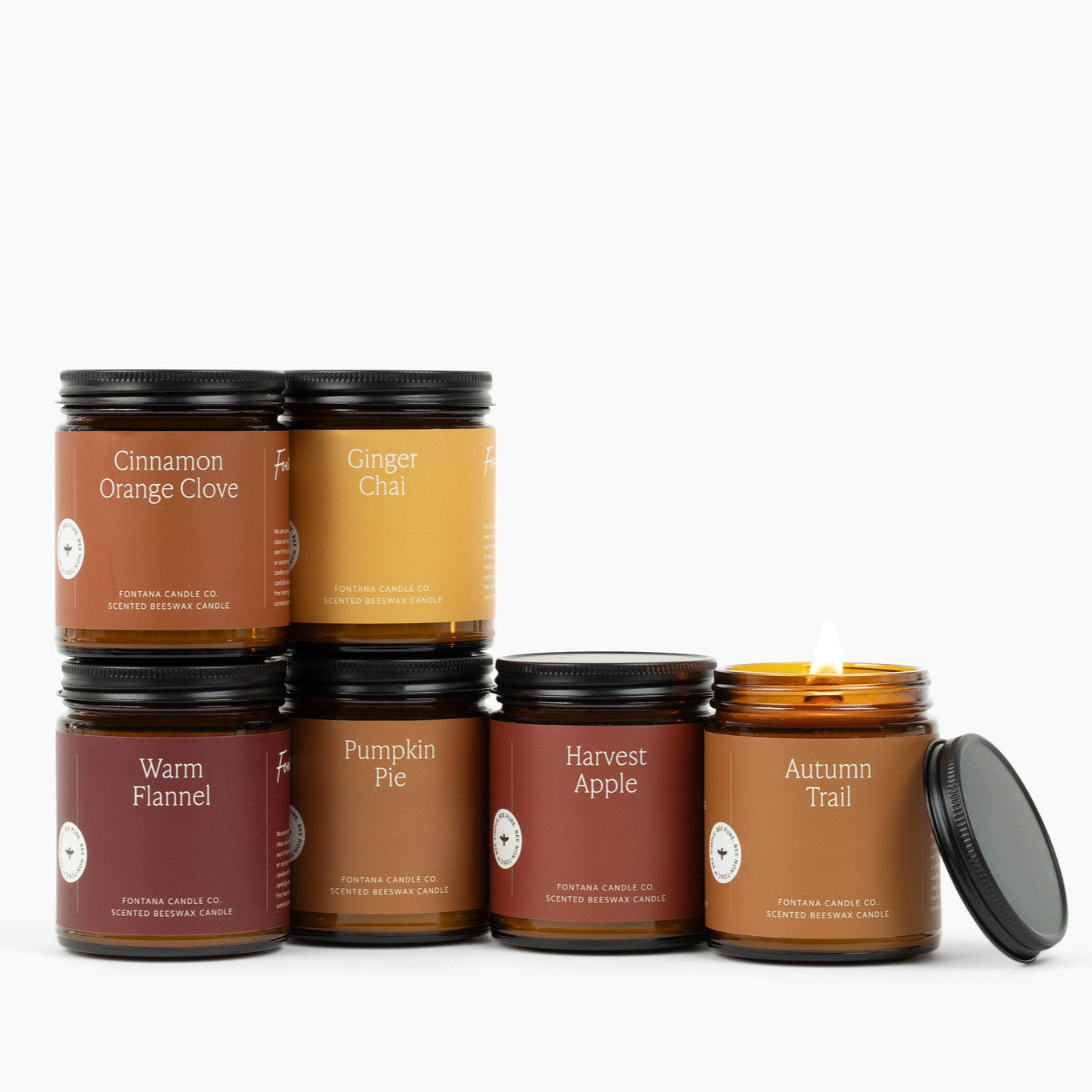 6 amber glass jar candles on a white background: Cinnamon Orange Clove, Ginger Chai, Warm Flannel, Pumpkin Pie, Harvest Apple, and Autumn Trail.