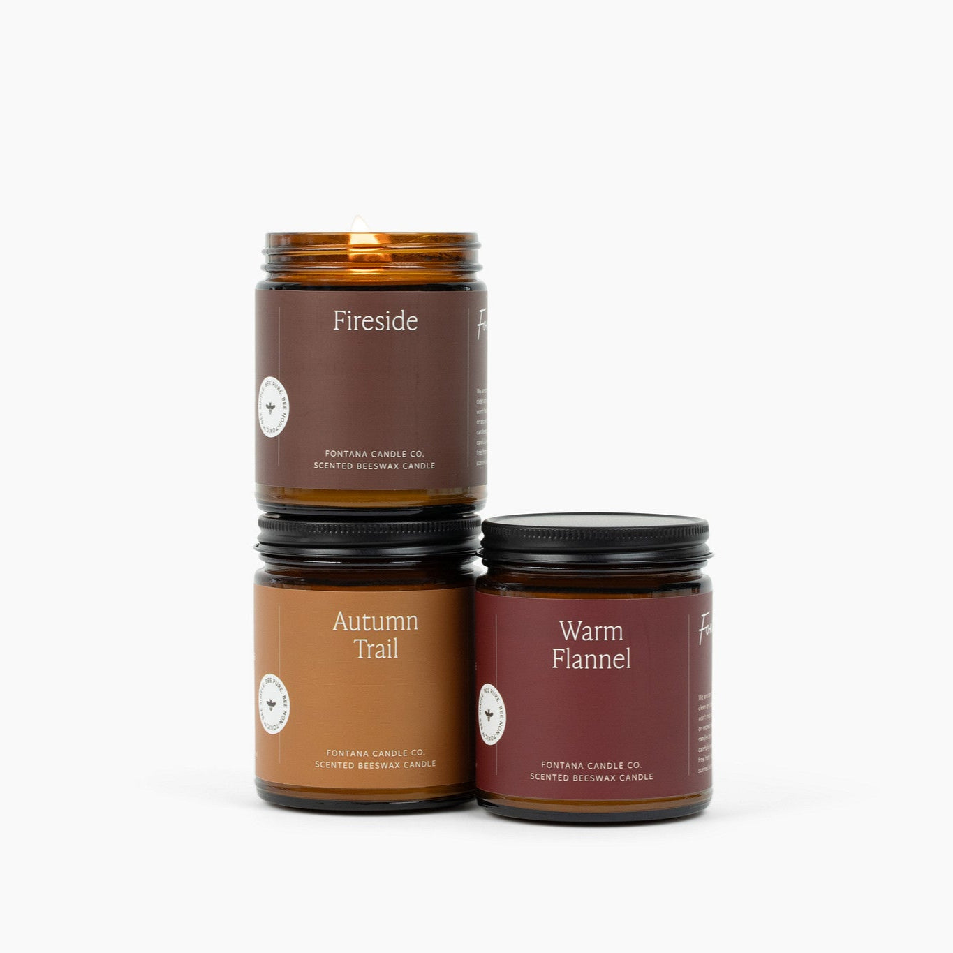 Three candles with labels 'Fireside', 'Autumn Trail', and 'Warm Flannel' on a white background.
