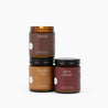 Three candles with labels 'Fireside', 'Autumn Trail', and 'Warm Flannel' on a white background.