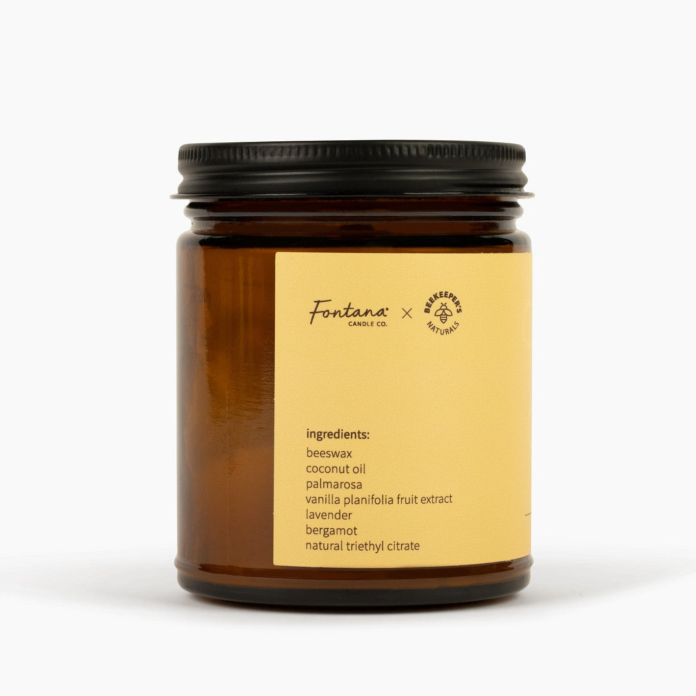 Amber candle jar with black lid and gold label on a white background