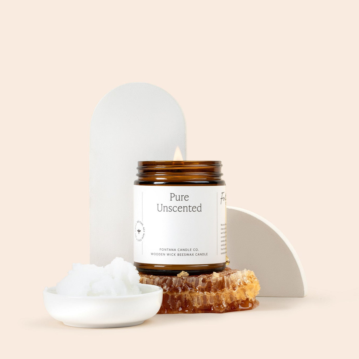 Amber glass jar candle 'Pure Unscented' with a scoop of coconut oil and a honeycomb. on a beige background.