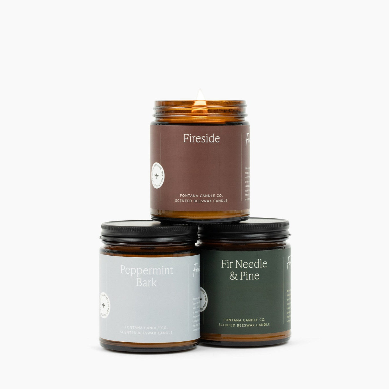 Three amber glass jar candles on a white background: Fireside, Peppermint Bark, Fir Needle and Pine.