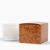 Unlit 3 wick candle in a white glass vessel with an orange box to the right of it with the ingredients: beeswax, coconut oil, sweet orange, cinnamon oil, and clove oil. 