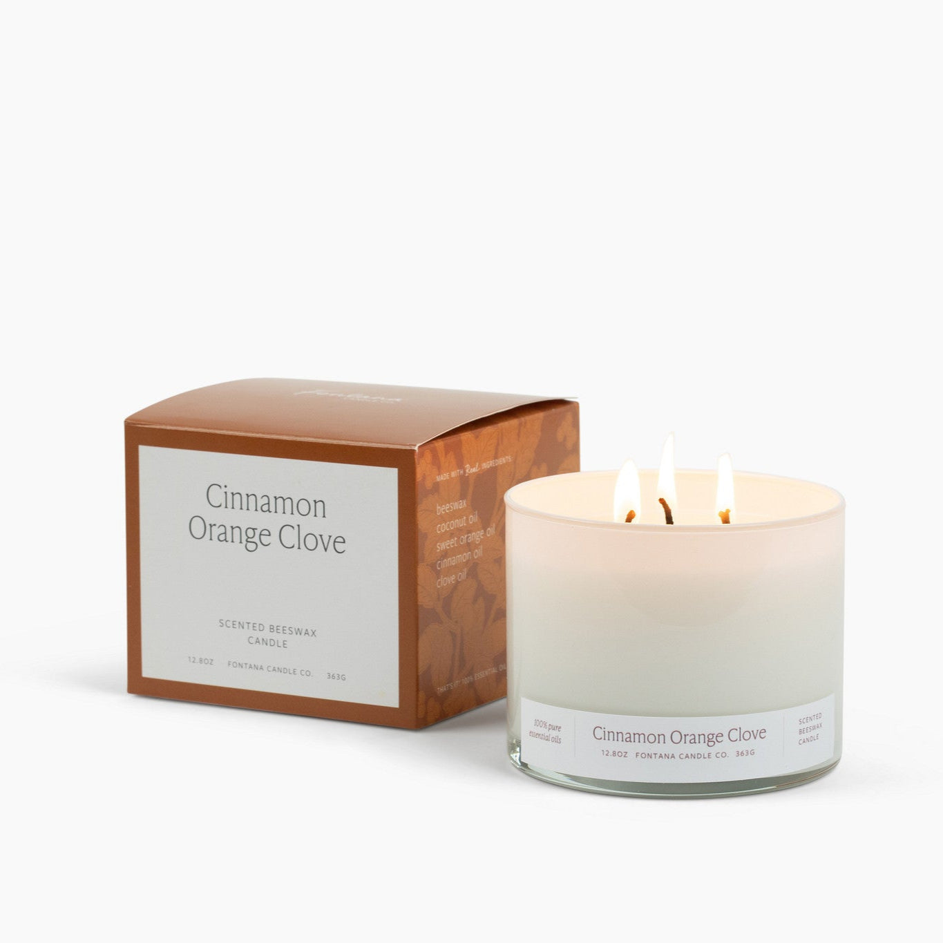 Lit 3 wick candle in a white glass vessel with an orange Cinnamon Orange Clove box to the left of it. 