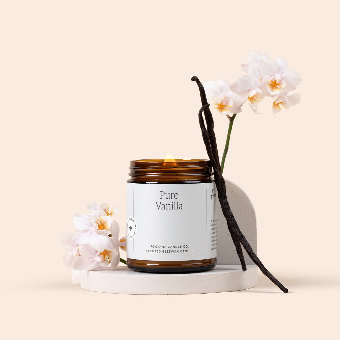 Pure Vanilla amber glass jar candle with vanilla beans and flowers on a cream background.
