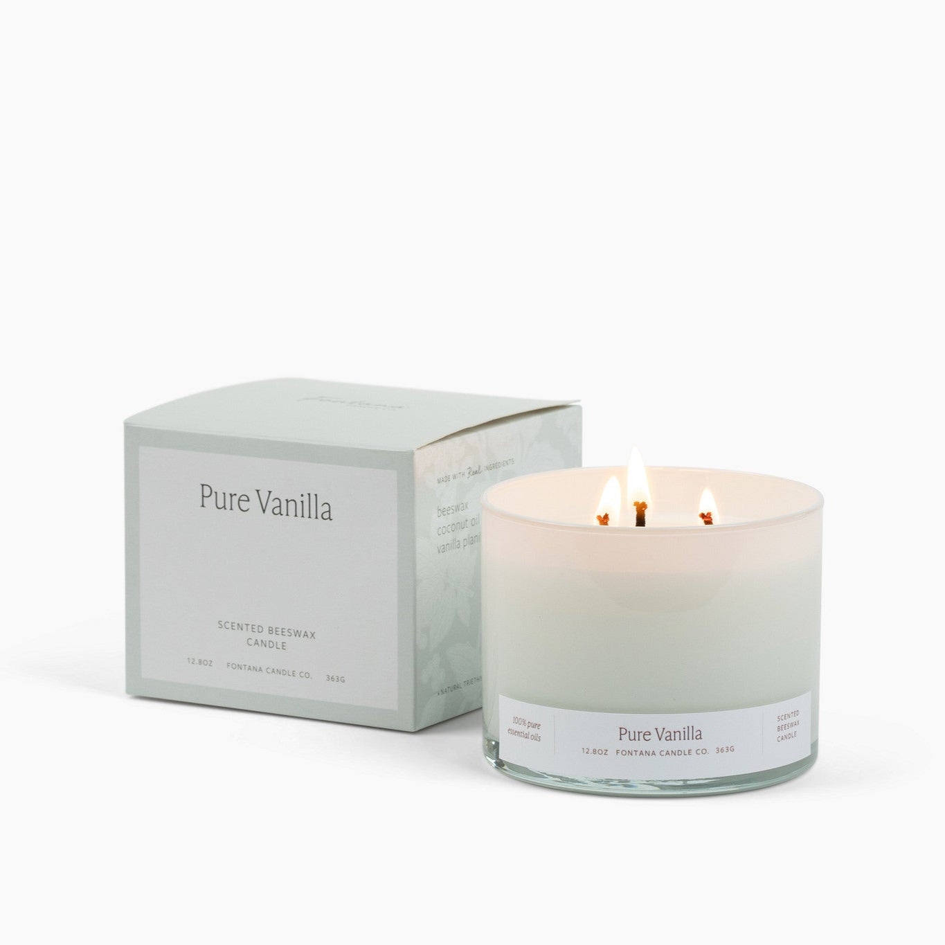Lit 3 Wick Candle in a white glass vessel with a white box to the left of it with the scent Pure Vanilla.