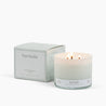 Lit 3 Wick Candle in a white glass vessel with a white box to the left of it with the scent Pure Vanilla.