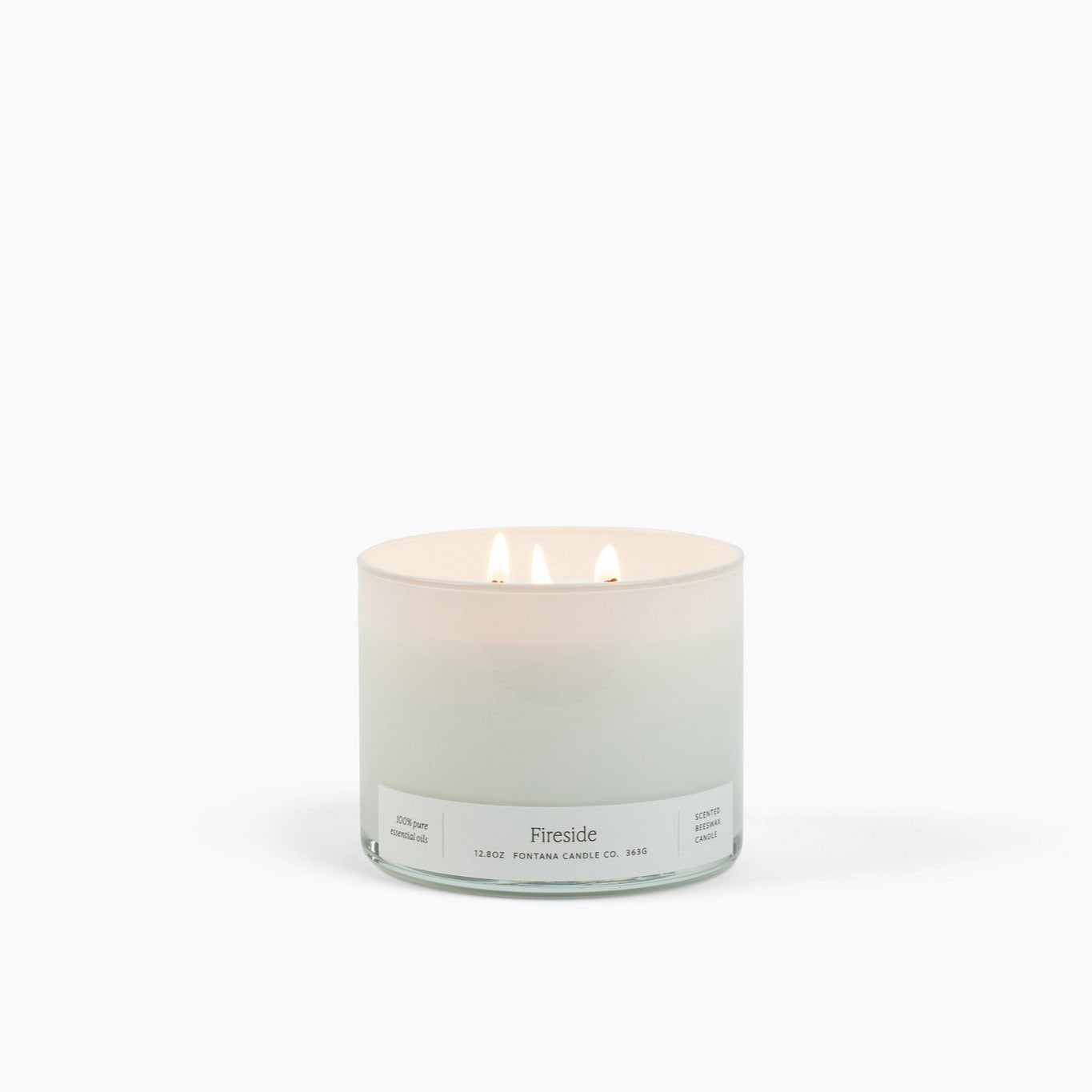 Lit 3 wick candle burning in a white glass container with a Fireside scent label. 