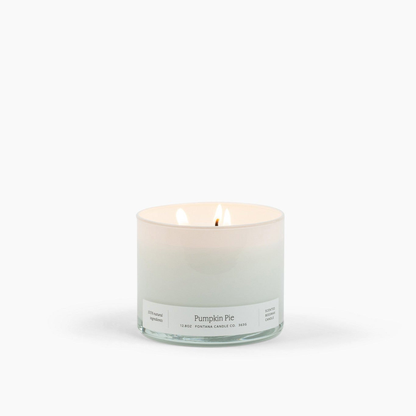 Lit 3 wick candle burning in a white glass container with a Pumpkin Pie scent label. 