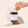 Amber glass jar candle 'Pure Unscented' with a scoop of coconut oil and a honeycomb. on a beige background.