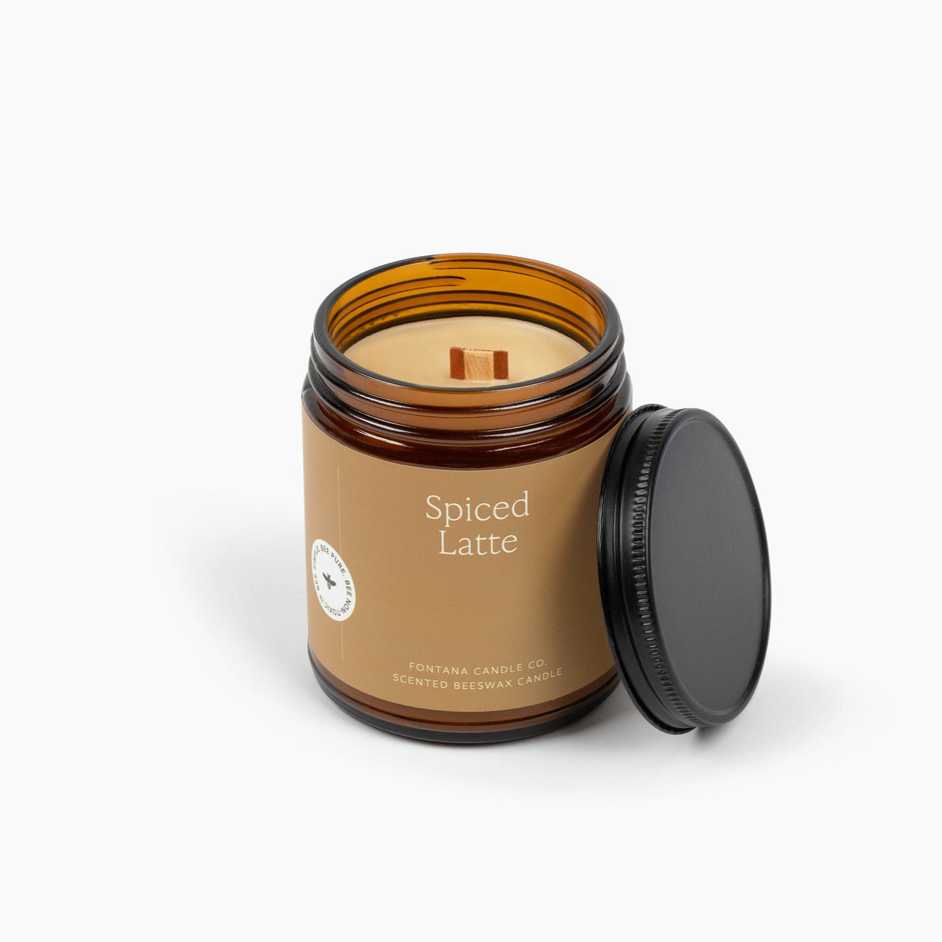 Unlit amber glass jar candle with a brown label and wooden wick. 