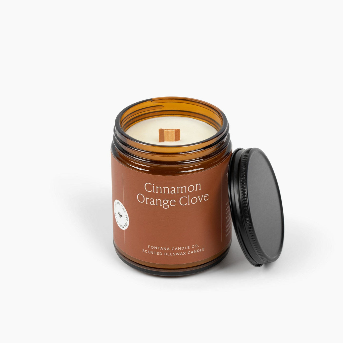 Amber glass jar candle with a deep orange label and a wooden wick. 