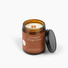 Amber glass jar candle with a deep orange label and a wooden wick. 