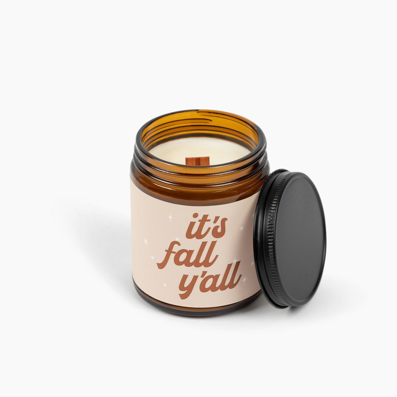 Unlit amber glass jar candle with the text It's Fall Y'all in brown.