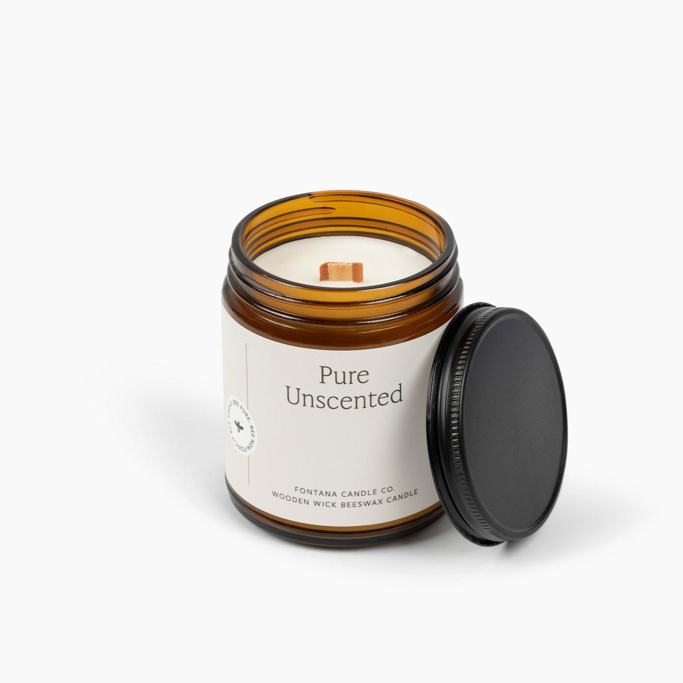 Unlit amber glass jar candle with a white label and wooden wick. 