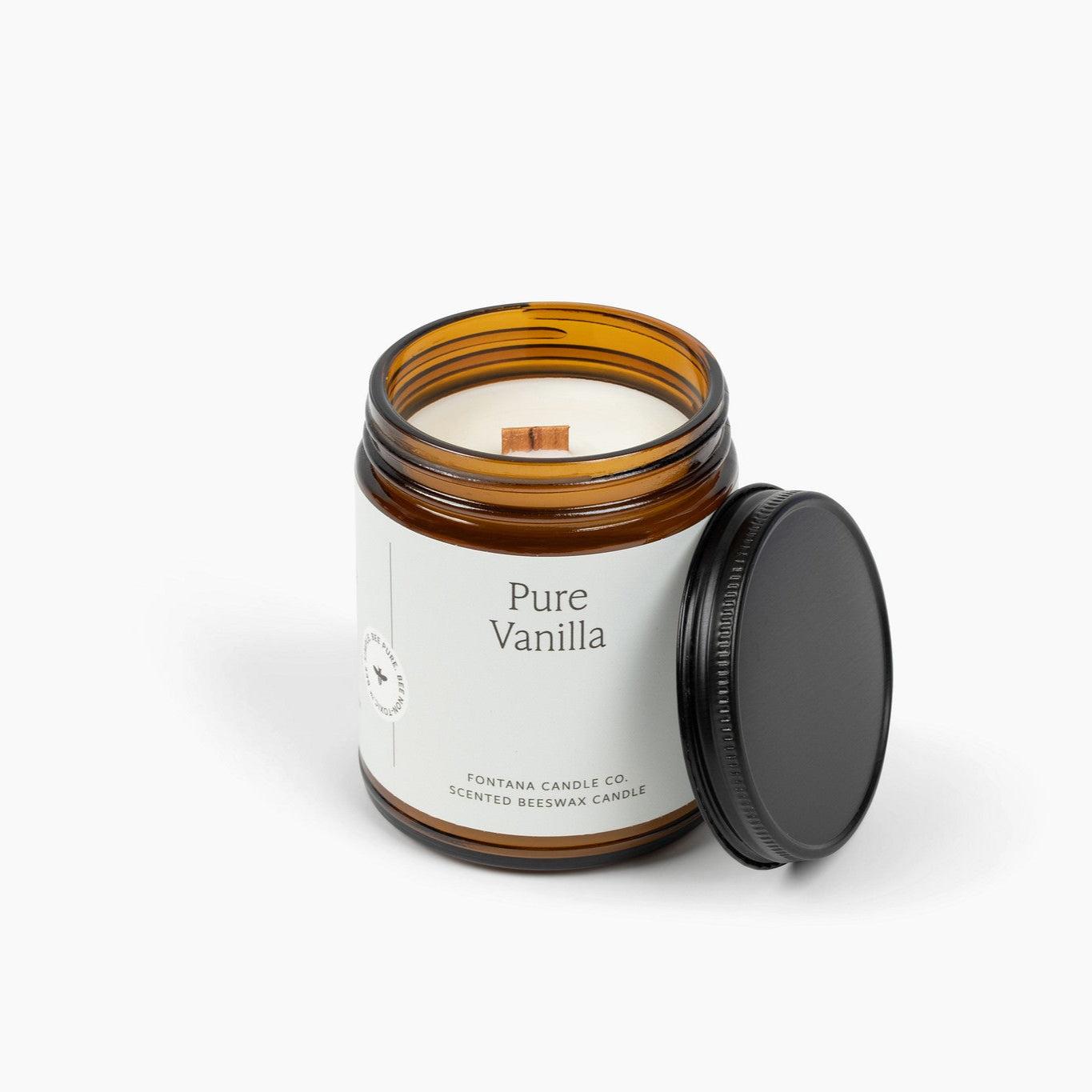 Unlit amber glass jar candle with a white label and wooden wick. 