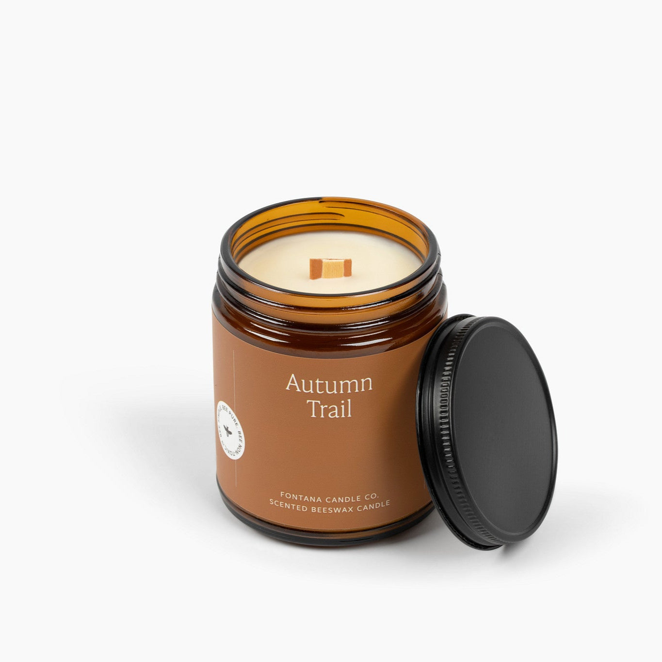 Unlit amber glass jar candle showing a deep brown label and a wooden wick.
