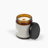 Unlit amber glass jar candle with a light gray label showing the wooden wick and the scent Cozy Cabin.