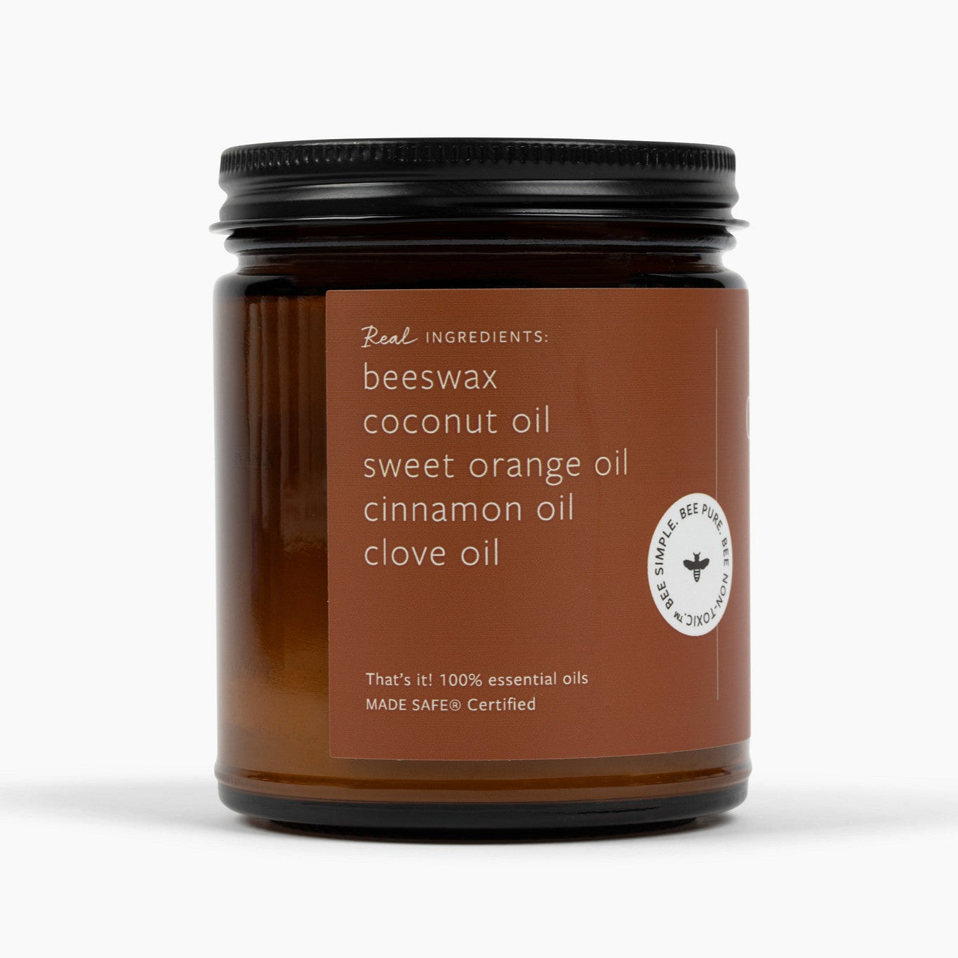 Side view of the amber glass jar candle with the deep orange label and ingredient list: beeswax, coconut oil, sweet orange oil, cinnamon oil, and clove oil. 